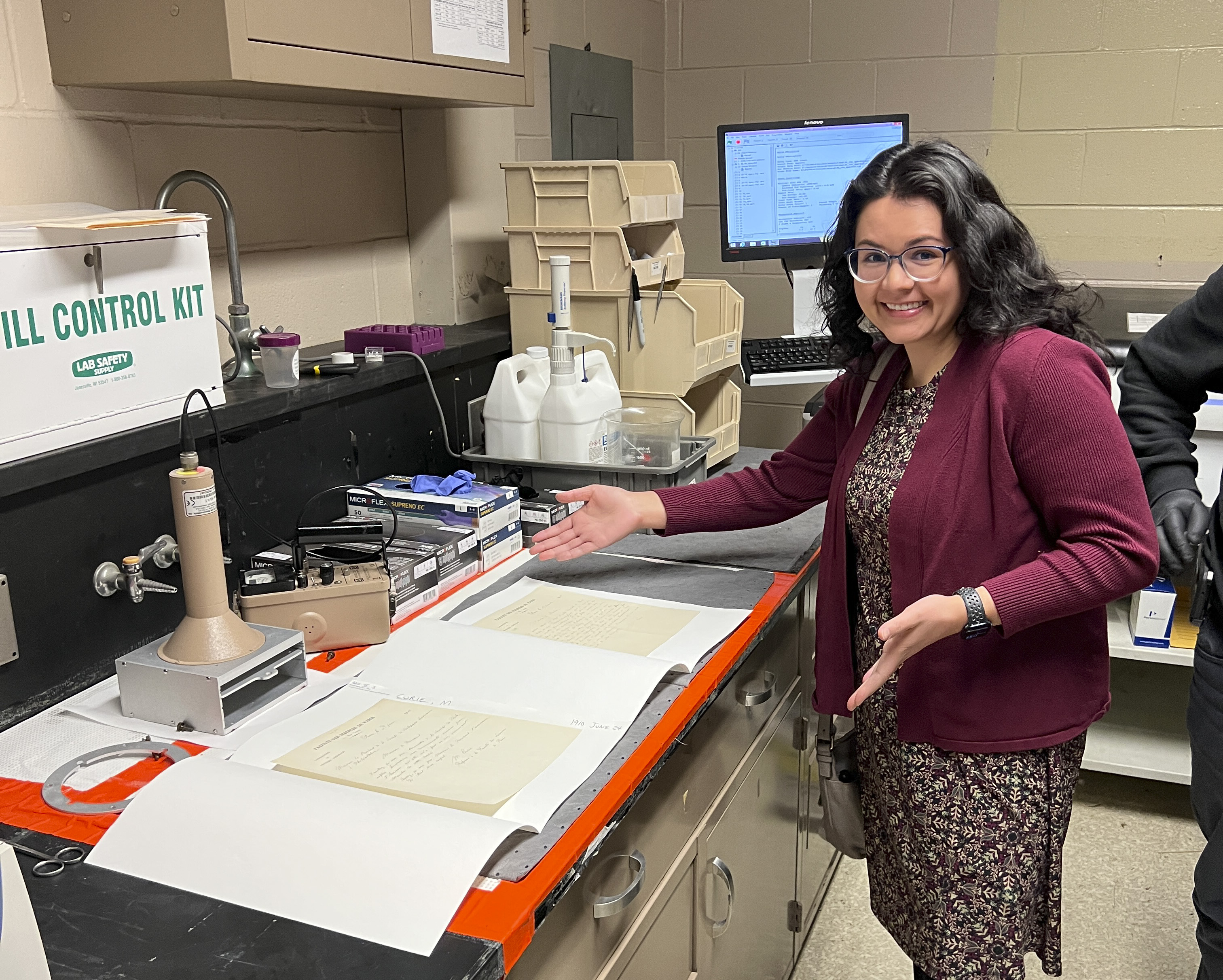 photo of woman posing in front of open folders with manuscript letters open inside