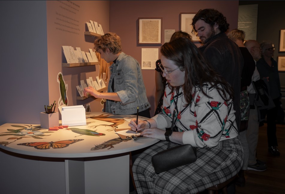 photo of people in gallery with one seated sketching at table