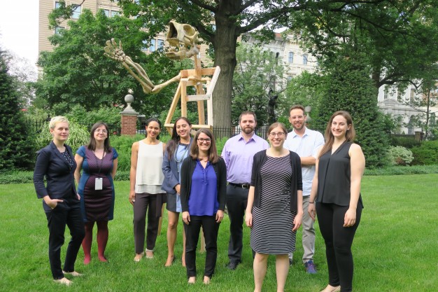 group standing in garden in front of giant sloth skeleton sculpture