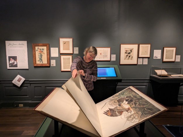 photo of woman turning the page of The Birds of America in the gallery