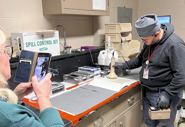 photograph of person taking a photograph of another person scanning a letter with equipment