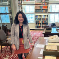 photo of woman standing alongside large table with documents displayed