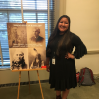 woman in black dress next to poster